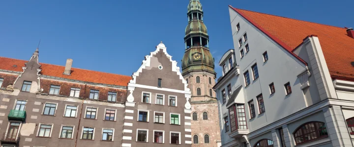 The House of the Black Heads in Riga, Latvia, features a tall structure topped with a prominent steeple, highlighting its grandeur.