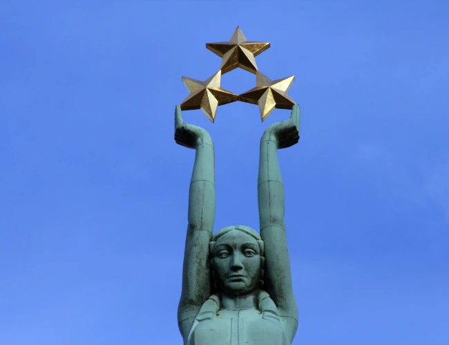  A statue of a woman in Latvia, gracefully holding up three stars, symbolizing hope and aspiration.