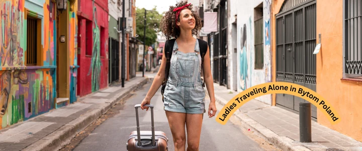 A woman walks down a street in Bytom, Poland, carrying a suitcase, embodying the spirit of solo female travel.