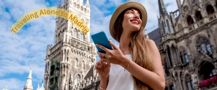 A woman in a hat holds a cell phone, capturing her solo travel experience in Madrid.